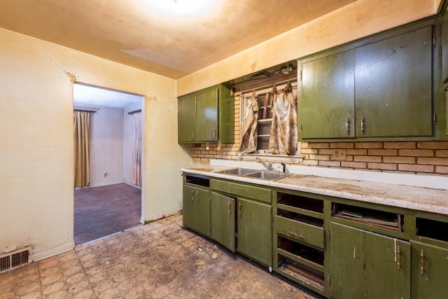 kitchen with visible vents, dark floors, light countertops, green cabinets, and a sink