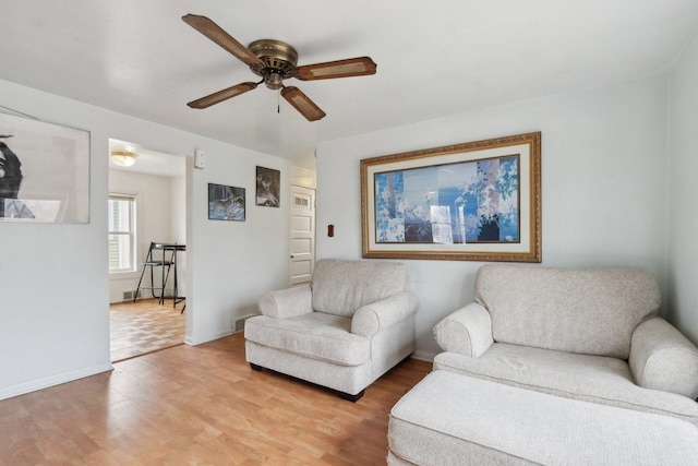 living area featuring ceiling fan, light wood-type flooring, and baseboards