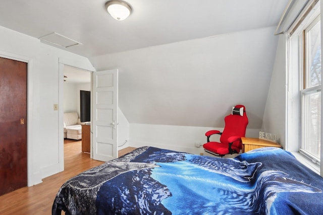 bedroom featuring vaulted ceiling, wood finished floors, and attic access