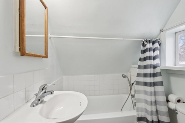 bathroom with shower / bath combination with curtain, lofted ceiling, a sink, and toilet