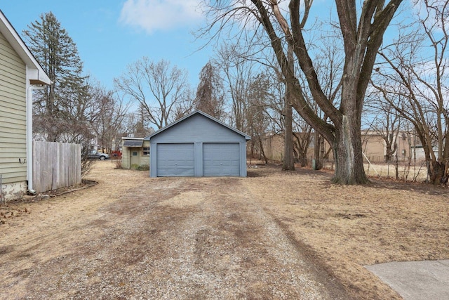 view of yard featuring a garage, fence, and an outbuilding