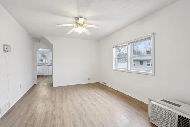 interior space with a ceiling fan, visible vents, a sink, and light wood finished floors