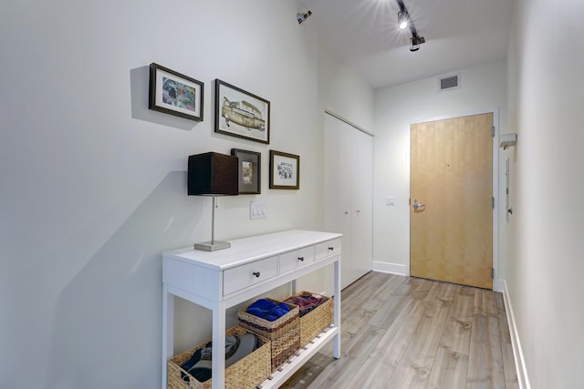 interior space with light wood-style flooring, track lighting, visible vents, and baseboards