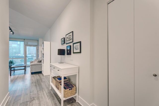 hall with expansive windows, baseboards, and light wood-style floors