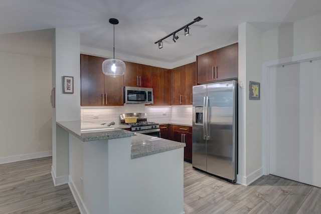 kitchen featuring a peninsula, light wood-style flooring, stainless steel appliances, and decorative backsplash