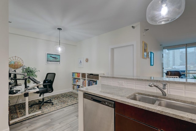 kitchen featuring light wood-style floors, dishwasher, light stone counters, and a sink