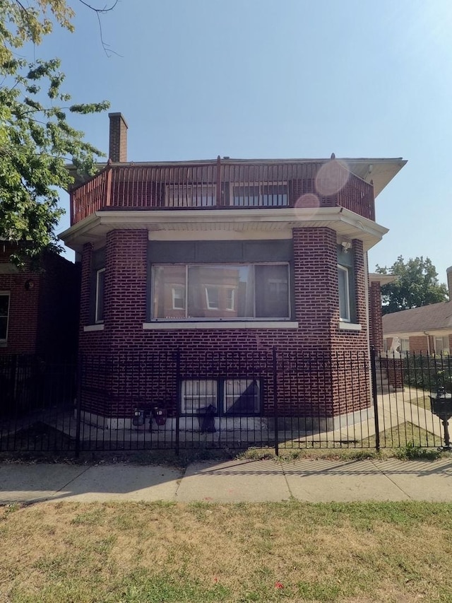 view of front of house featuring a chimney, fence, and brick siding