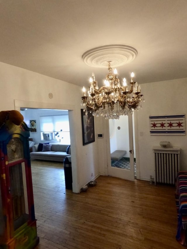 dining area with lofted ceiling, radiator, a notable chandelier, and wood finished floors