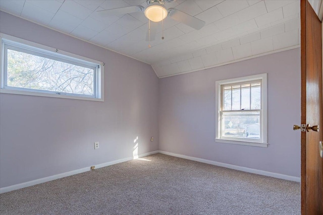 unfurnished room with carpet, vaulted ceiling, plenty of natural light, and baseboards