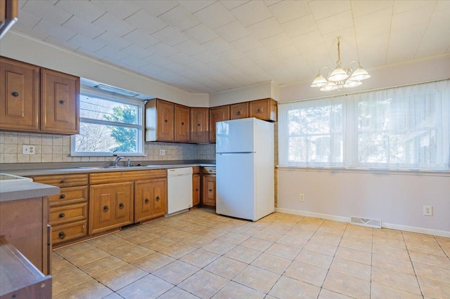 kitchen with brown cabinets, a notable chandelier, visible vents, decorative backsplash, and white appliances