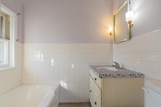 bathroom with toilet, vanity, a garden tub, and tile walls