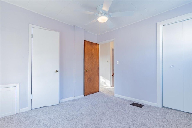 unfurnished bedroom featuring carpet floors, visible vents, a ceiling fan, baseboards, and a closet