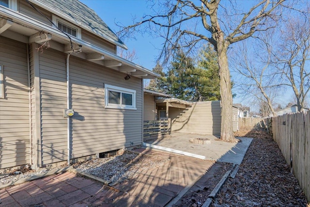 view of side of property featuring a fenced backyard, a shingled roof, and a patio