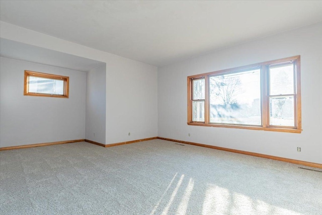 unfurnished room with light carpet, a wealth of natural light, and baseboards