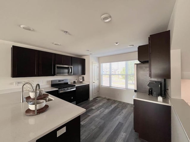 kitchen with appliances with stainless steel finishes, dark wood-style flooring, light countertops, and a sink