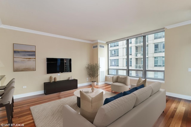 living area featuring a wealth of natural light, ornamental molding, and wood finished floors