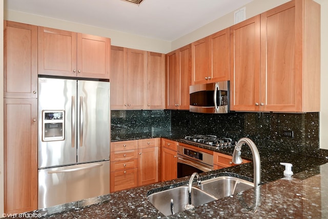 kitchen featuring dark stone counters, stainless steel appliances, and decorative backsplash