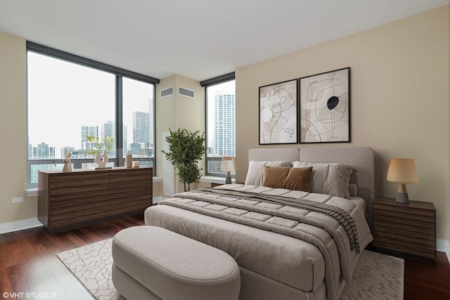 bedroom featuring multiple windows, dark wood-type flooring, and a city view