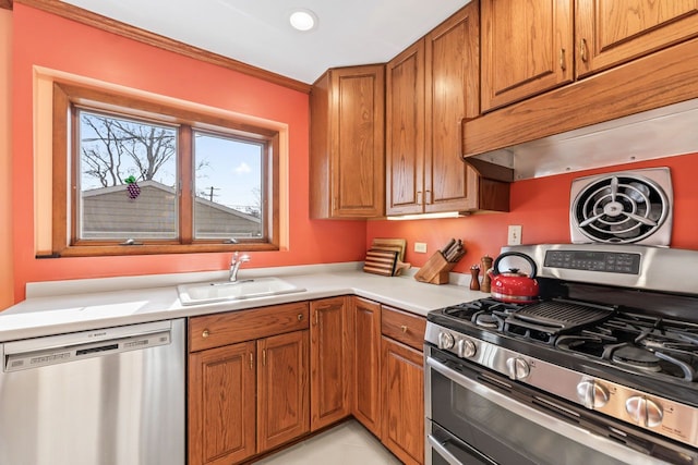 kitchen featuring a sink, stainless steel appliances, brown cabinetry, and light countertops