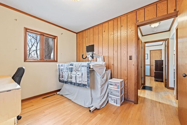 home office featuring light wood-style flooring, wood walls, baseboards, and ornamental molding