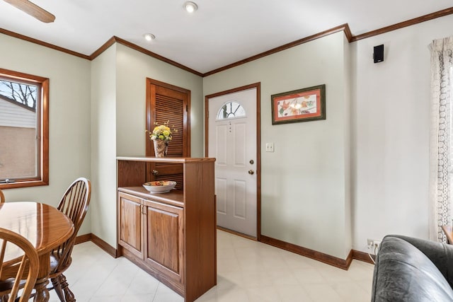 foyer entrance featuring crown molding, light floors, and baseboards