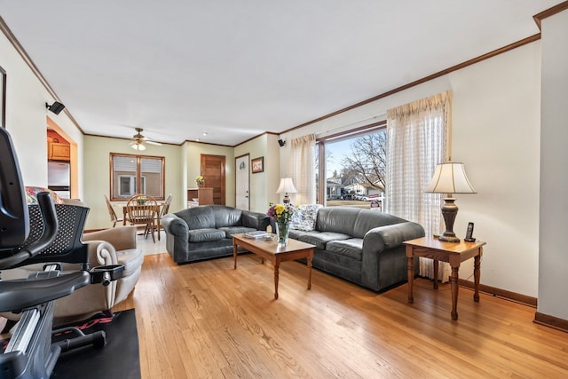 living area featuring baseboards, crown molding, light wood-style floors, and a ceiling fan