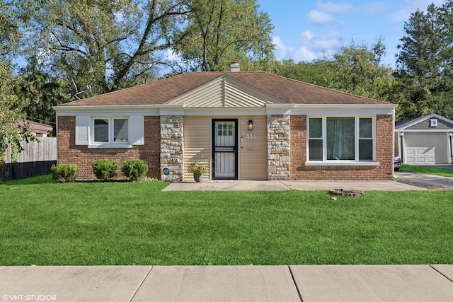 view of front of property featuring an outbuilding, brick siding, a front yard, and fence