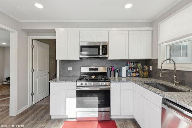 kitchen with white cabinets, light stone countertops, stainless steel appliances, light wood-type flooring, and a sink