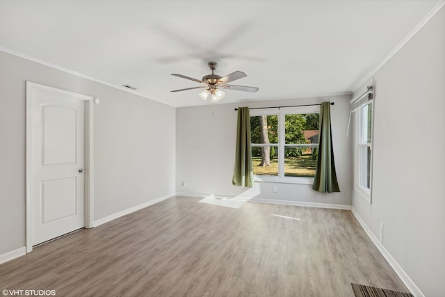 spare room with ornamental molding, light wood-type flooring, visible vents, and baseboards