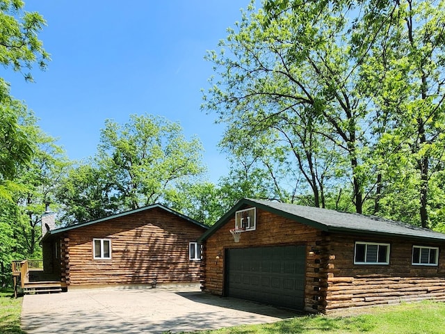 log-style house featuring an outdoor structure, driveway, a wooden deck, log exterior, and a chimney