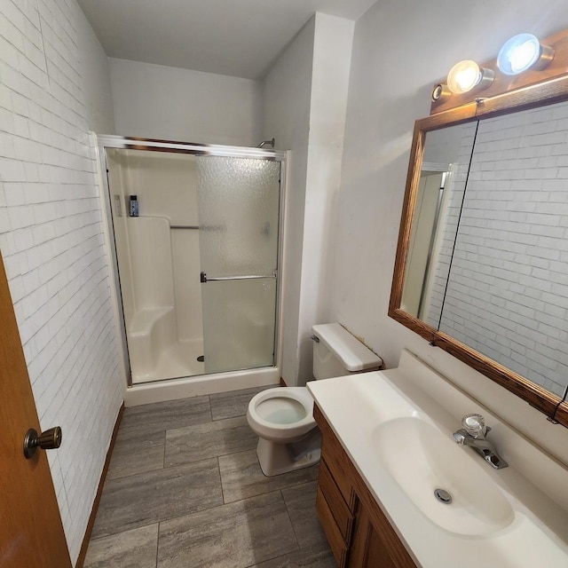 bathroom featuring toilet, a stall shower, wood tiled floor, and vanity