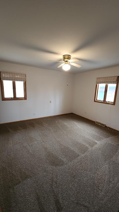 carpeted spare room with ceiling fan