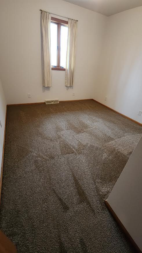 empty room with carpet flooring, visible vents, and baseboards