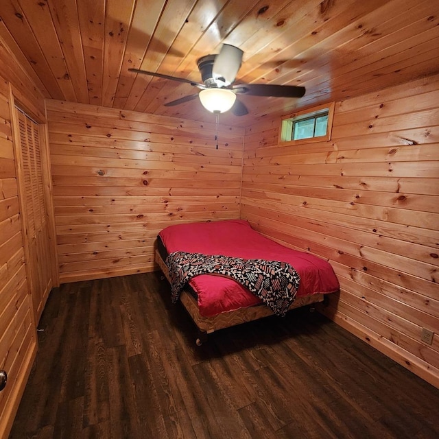 bedroom with wood walls, wooden ceiling, dark wood finished floors, and a ceiling fan