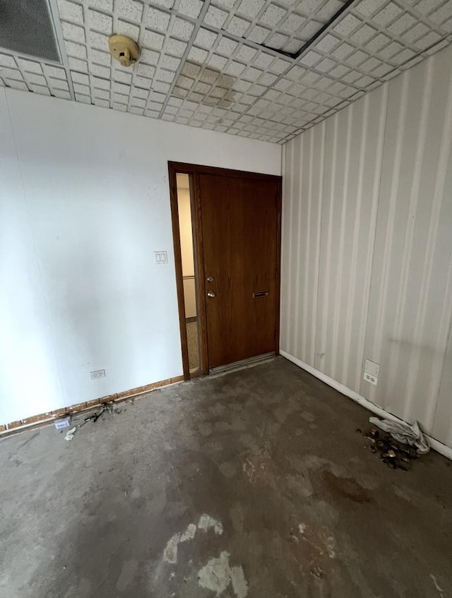 unfurnished room with baseboards and concrete flooring