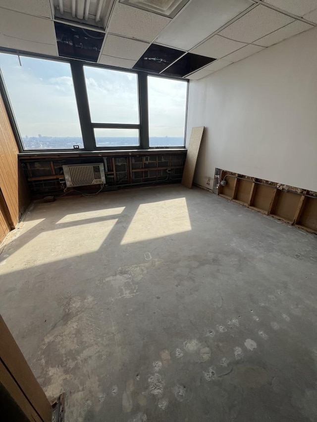 unfurnished room featuring a healthy amount of sunlight, a paneled ceiling, and unfinished concrete floors