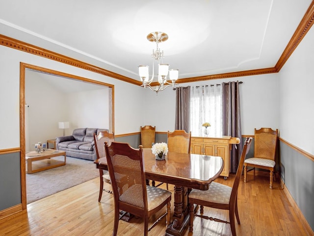 dining space with crown molding, light wood-style flooring, and a notable chandelier