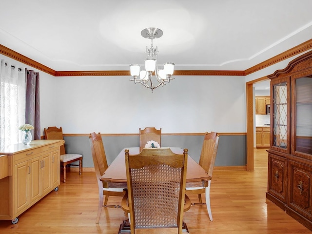 dining room featuring crown molding, light wood-type flooring, baseboards, and a notable chandelier