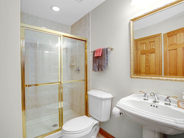 bathroom with a sink, a shower stall, and toilet