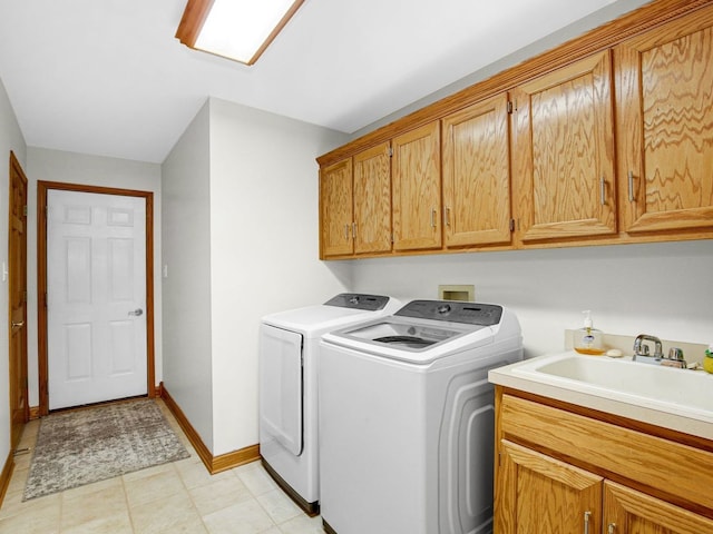 washroom with independent washer and dryer, a sink, cabinet space, and baseboards