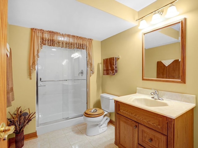 bathroom featuring toilet, vanity, a shower stall, baseboards, and tile patterned floors