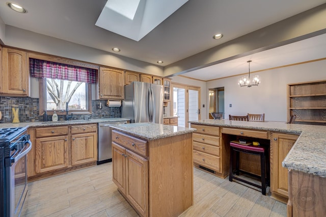 kitchen with light wood finished floors, tasteful backsplash, appliances with stainless steel finishes, light stone counters, and a sink