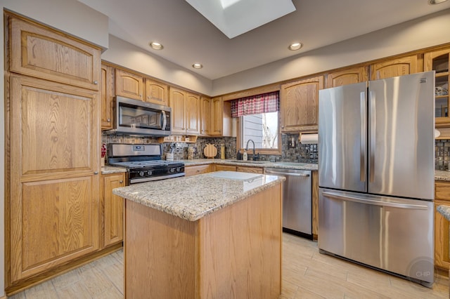 kitchen featuring light stone countertops, a skylight, appliances with stainless steel finishes, and a sink