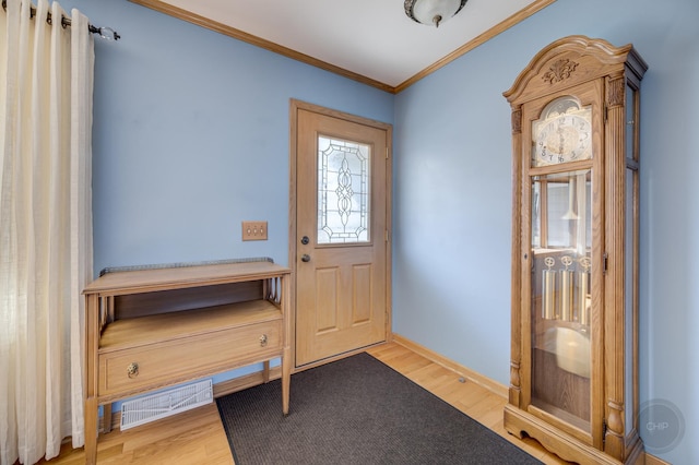 foyer with baseboards, visible vents, ornamental molding, and wood finished floors