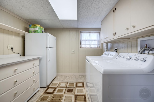 laundry room with baseboards, cabinet space, light floors, and separate washer and dryer