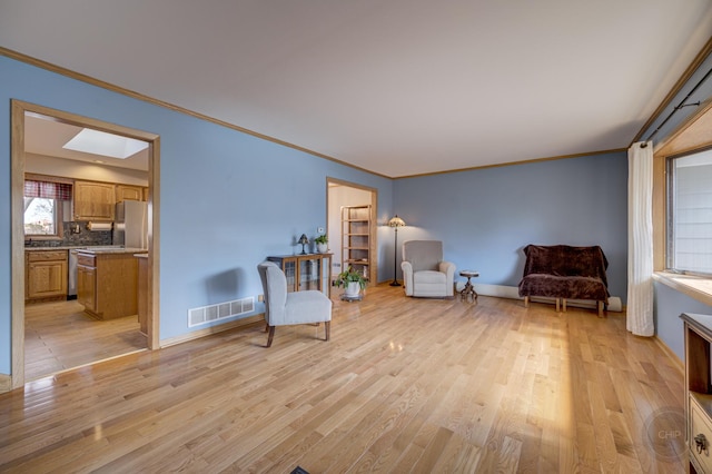 living area featuring a skylight, visible vents, light wood-style floors, and ornamental molding