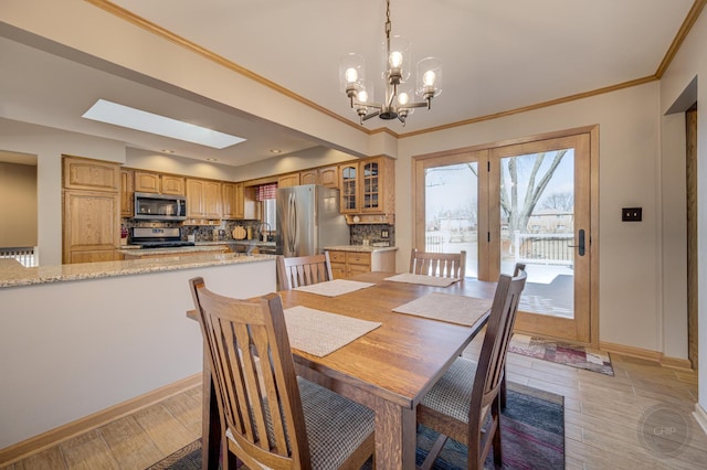 dining area featuring baseboards, crown molding, light wood-style flooring, and a healthy amount of sunlight