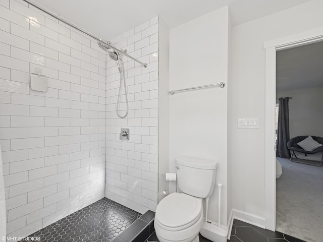 full bath with a tile shower, tile patterned floors, toilet, and baseboards