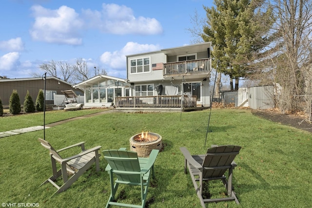 back of property with a yard, fence, a deck, and an outdoor fire pit