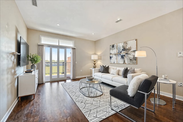 living area with hardwood / wood-style floors, visible vents, and baseboards